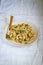 traditional soviet russian pasta dish, vermicelli, navy pasta, with meat on a white plate on a light fabric background. Minimalism