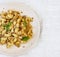 traditional soviet russian pasta dish, vermicelli, navy pasta, with meat on a white plate on a light fabric background. Minimalism