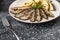 Traditional Spanish barbecue sardines with boiled potatoes, on a plate close up. horizontal