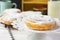 Traditional Spanish or Philippine pastry ensaimada. Powdered, on cooling rack and white cake stand. Bottle of milk, straw.