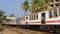 Traditional Sri Lankan train with open doors and passengers on the footboard passes the station