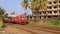 Traditional Sri Lankan train with open doors and passengers on the footboard passes the station