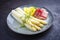 Traditional steamed white asparagus with cured ham and boiled potatoes garnished with butter on a Nordic design plate