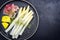 Traditional steamed white asparagus with cured ham and boiled potatoes garnished with butter sauce on a Nordic design plate