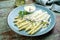 Traditional steamed white asparagus garnished with sauce hollandaise and herbs on a design plate