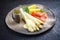 Traditional steamed white asparagus with smoked salmon slices and boiled potatoes garnished with sauce hollandaise
