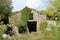 Traditional stone house abandoned and left in ruins partially overgrown with crawler plants surrounded with high grass and trees