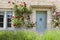 Traditional stone house with blue doors, red roses, flowering lavender