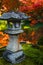 Traditional stone lantern and red maples in a Japanese garden during autumn