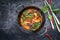 Traditional Thai kaeng phet red curry with vegetables in a wok with copy space left