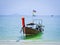 Traditional Thai longtail boat for tourists moored near the beach on the background of the azure sea.