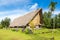 Traditional thatched yapese men`s meeting house faluw or fale and a bank of stone money rai. Yap island, Micronesia, Oceania.