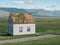 Traditional turf covered house in Glaumbaer, northwestern Iceland. Agricultural fields with horses, and snow-covered mountains in