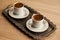 Traditional Turkish coffee in a patterned white cup in a metal tray on an oak coffee table