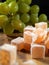 Traditional Turkish and Greek rose flavor jelly candy in sugar powder and green grapes on a wooden board and black background.