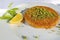 Traditional turkish kunefe dessert with grated pistachios, sliced lemon and mint on plate.