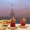 Traditional Turkish tea set of 2 tea glasses with Maiden Tower Istanbul silhouette background.