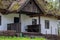 Traditional Ukrainian ancient residential rural house. White painted walls, small windows, reed roof. Low hedge of willow vines.