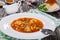 Traditional Ukrainian or Russian vegetable soup, borscht cooked in meat broth with new potatoes in white wide rim dish. sour crea