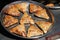 Traditional Uzbek patties samsa with chicken meat, lying on a large metal dish