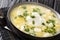 Traditional Venezuelan breakfast of chicken broth, with potatoes, eggs, cheese and cilantro close-up in a bowl. horizontal