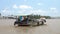 Traditional Vietnamese boat sailing on the Mekong River in front of coconut processing factories, Vietnam