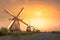 Traditional village with dutch windmills and river at sunset, Holland, Netherlands.