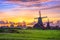 Traditional village with dutch windmills and river at sunset, Holland, Netherlands.