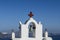 Traditional white and red belfry with cross and bell of Greek orthodox church. Oia, Santorini, Greece