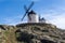 Traditional whitewashed Spanish windmills in La Mancha on a hilltop above Consuegra