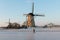 Traditional windmills and frozen canal with lonely skater, Kinderdijk, Netherlands