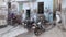 Traditional women and parked motorcycles in front of house in small alley.