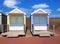 Traditional wooden beach huts painted in bright colours in bright summer sunshine with blue sky and white clouds