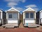 Traditional wooden beach huts painted in bright colours in bright summer sunshine with blue sky and white clouds