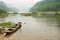 Traditional wooden boat tied at a river bank in rainy weather in Chengyang, Guangxi, China.