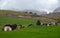 Traditional wooden cottage mountain houses in the green field in the dolomites. Housing in Italian apls. Alpine region