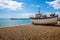 A traditional wooden fishing boat rests at the waters edge in old Hastings, Sussex, UK