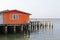 Traditional wooden house of fisherman in orange built on concrete stilts in Thailand.