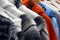 Traditional woolen coats for sale on a market stall, black, white, orange and blue