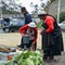 Traditionally dressed Ecuadorian women inspecting vegetables in a market