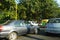 Traffic of Cars, Autos and Bikes on Indian Road in day time. People are present standing under trees away from sun light. : Punjab