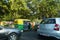 Traffic of Cars, Autos and Bikes on Indian Road in day time. People are present standing under trees away from sun light. : Punjab