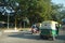 Traffic of Cars, Autos and Bikes on Indian Road in day time. People are present standing under trees away from sun light. : Punjab