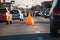 traffic cone in the middle of a busy intersection, with cars and people rushing by