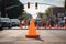 traffic cone in the middle of a busy intersection, with cars and people rushing by