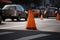 traffic cone in the middle of busy intersection, with cars zooming past
