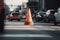 traffic cone in the middle of busy intersection, with cars zooming past