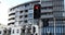 A traffic light with a red light on near a brand new modern residential apartment building.