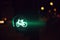 traffic light showing green bicycle symbol at night with colorful lights in blurred background