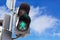 Traffic lights with the green light lit for pedestrians against blue sky background with clouds.